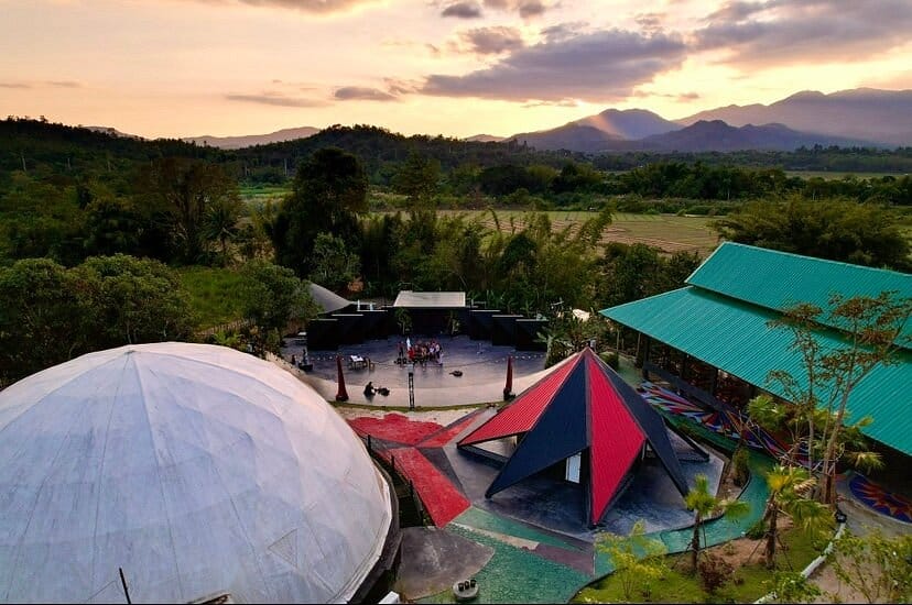 Dreamscape in Pai, Thailand at sunset: a geodesic dome and open-air pavilions, with rice fields and mountains behind